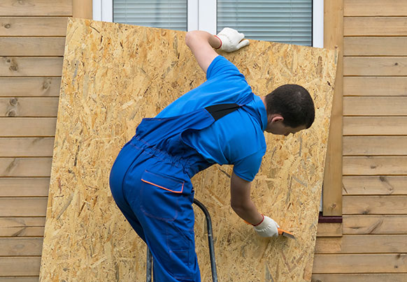 Man securing home windows with wood panel