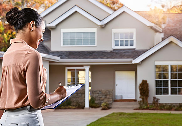 Person with a clipboard looking at a home 